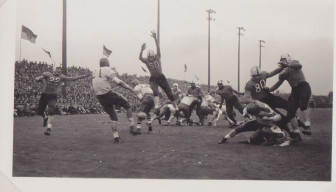 Black and white image of a Massillon player jumping on a kicked football.